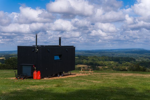 An off-grid HIDE n SEEK cabin at a field edge with sheep grazing in front
